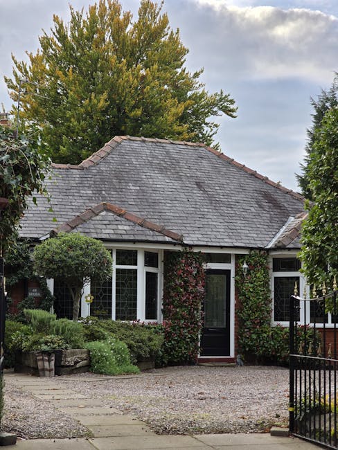 The image features the entrance to a traditional terraced house with a black front door framed by white decorative columns and intricate detailing above the doorway. A small flight of three stone step